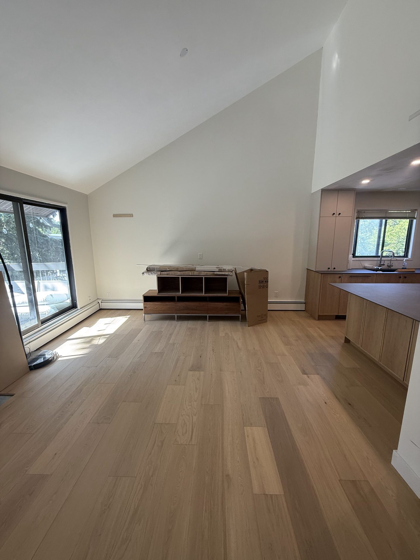Renovated open-concept living space with new hardwood flooring and kitchen